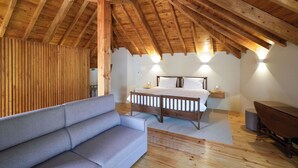 A bedroom with a wooden ceiling, a bed, a nightstand, a sofa, and wall-mounted lights.