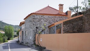A stone building with a red-tiled roof, a small window, and a door.