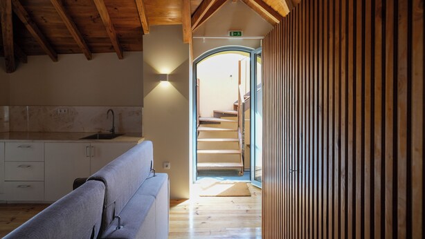 A modern interior with a wooden ceiling, a kitchen area, and a staircase leading to another level.