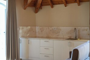 A kitchen with white cabinets, a marble backsplash, and a wooden ceiling.