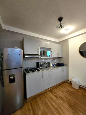 Eine kleine Küche mit Edelstahl-Kühlschrank, Mikrowelle, Toaster und Spüle.