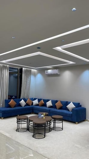 Una sala de estar moderna con un sofá modular, una mesa de centro redonda e iluminación empotrada en el techo.