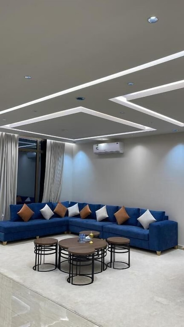 A modern living room with a sectional sofa, round coffee table, and recessed ceiling lighting.