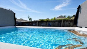 Une piscine à l’eau d’un bleu limpide, entourée d’une clôture en bois, sous un ciel dégagé.