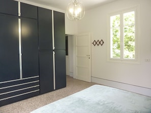 A bedroom with a bed, a wardrobe, a door, and a window. - Holiday Home 'Cascinetta' with Mountain View, Private Garden and Wi-Fi (Castello)