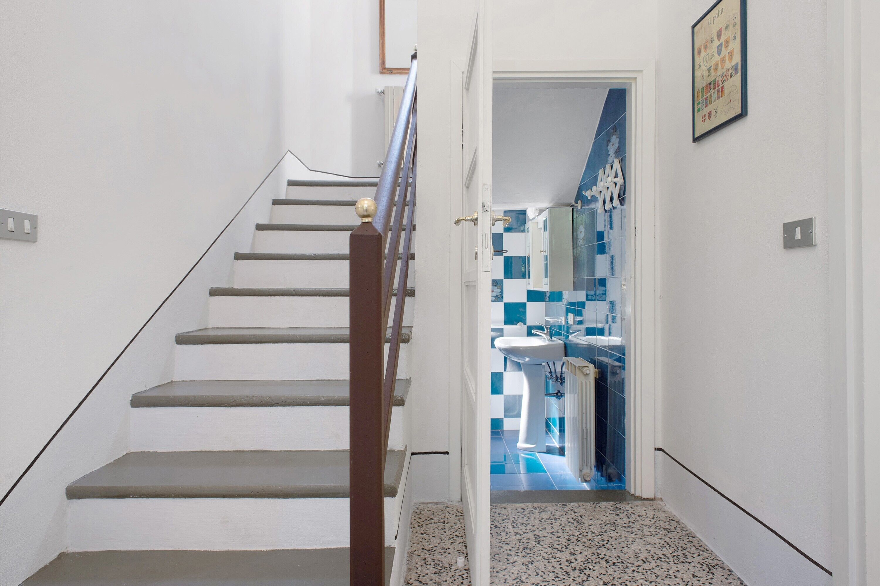 Eine Treppe führt zu einem Badezimmer mit blau-weißen Fliesen.