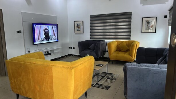 A modern living room with a flat-screen TV, two sofas, a coffee table, and artwork on the walls.