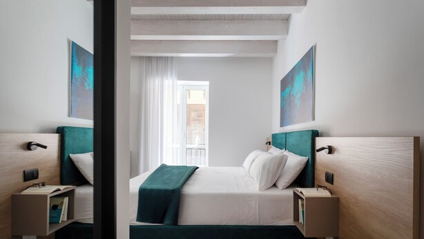 Una habitación de hotel moderna con una cama, mesitas de noche y obras de arte en las paredes.