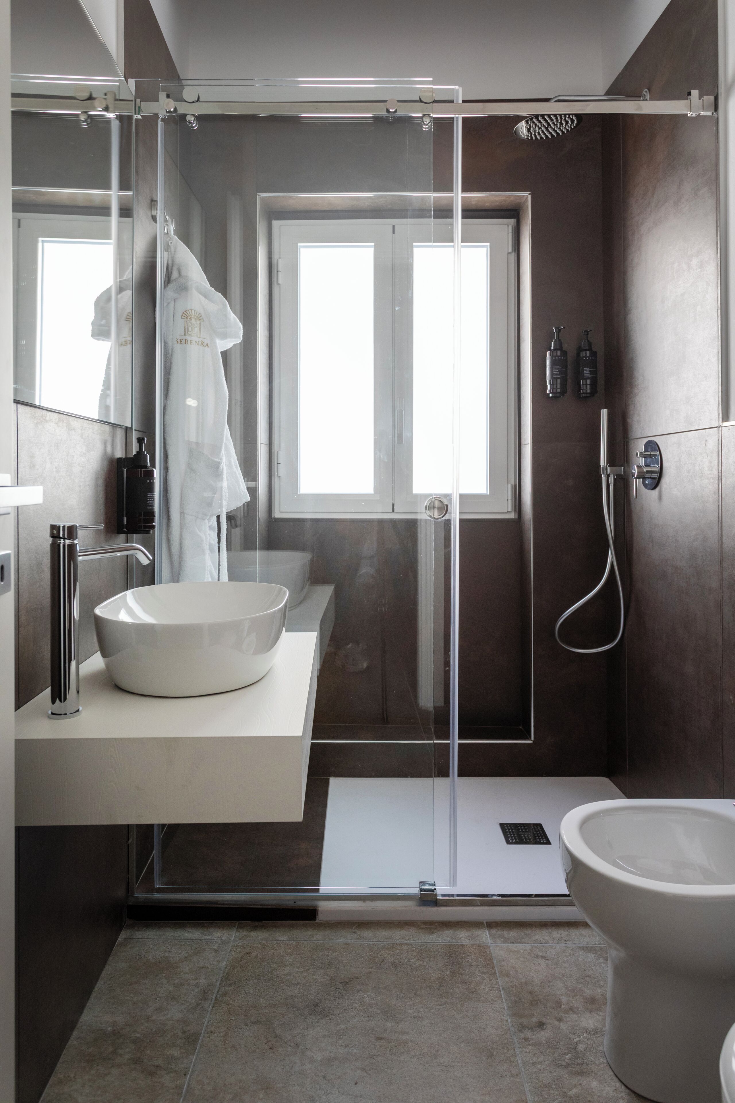 A modern bathroom with a glass-enclosed shower, a white sink, and a toilet.