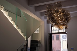 Uma escadaria com guarda-corpos de vidro e um lustre moderno.