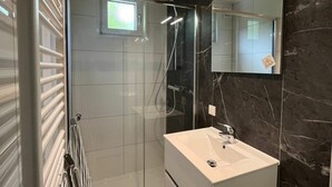 A modern bathroom with a glass shower enclosure, a white sink, and a large mirror. - Just Nature Light 4 (Arnhem)