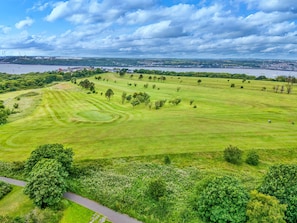 Ein Golfplatz mit einem Fluss und einer Stadt im Hintergrund.