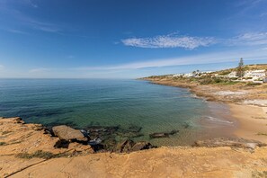 Un paysage côtier avec une eau d’un bleu limpide, une côte rocheuse et des bâtiments blancs situés sur le flanc d’une colline.