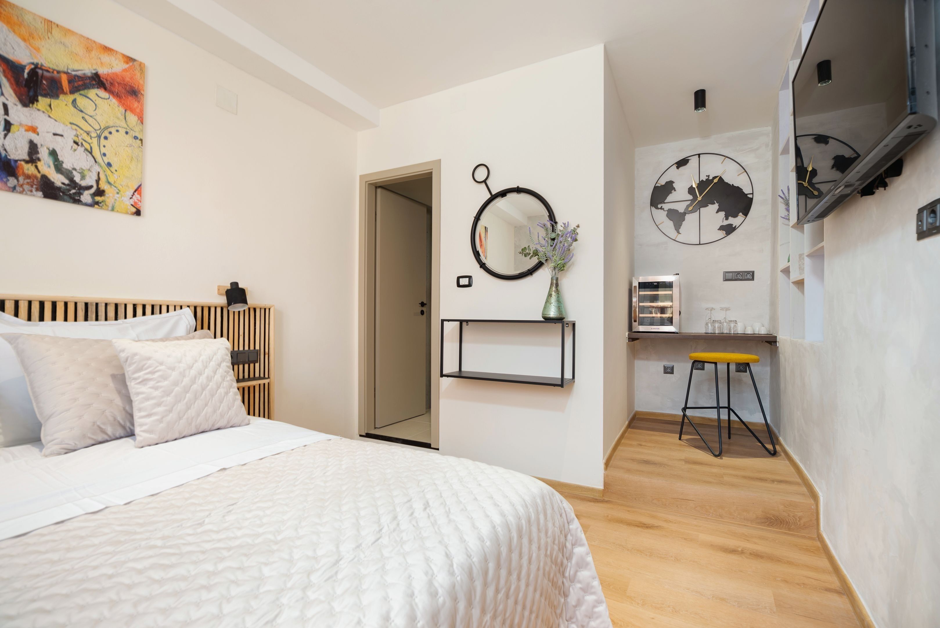 A bedroom with a bed, a wooden headboard, a wall-mounted mirror, a globe, and a small stool.