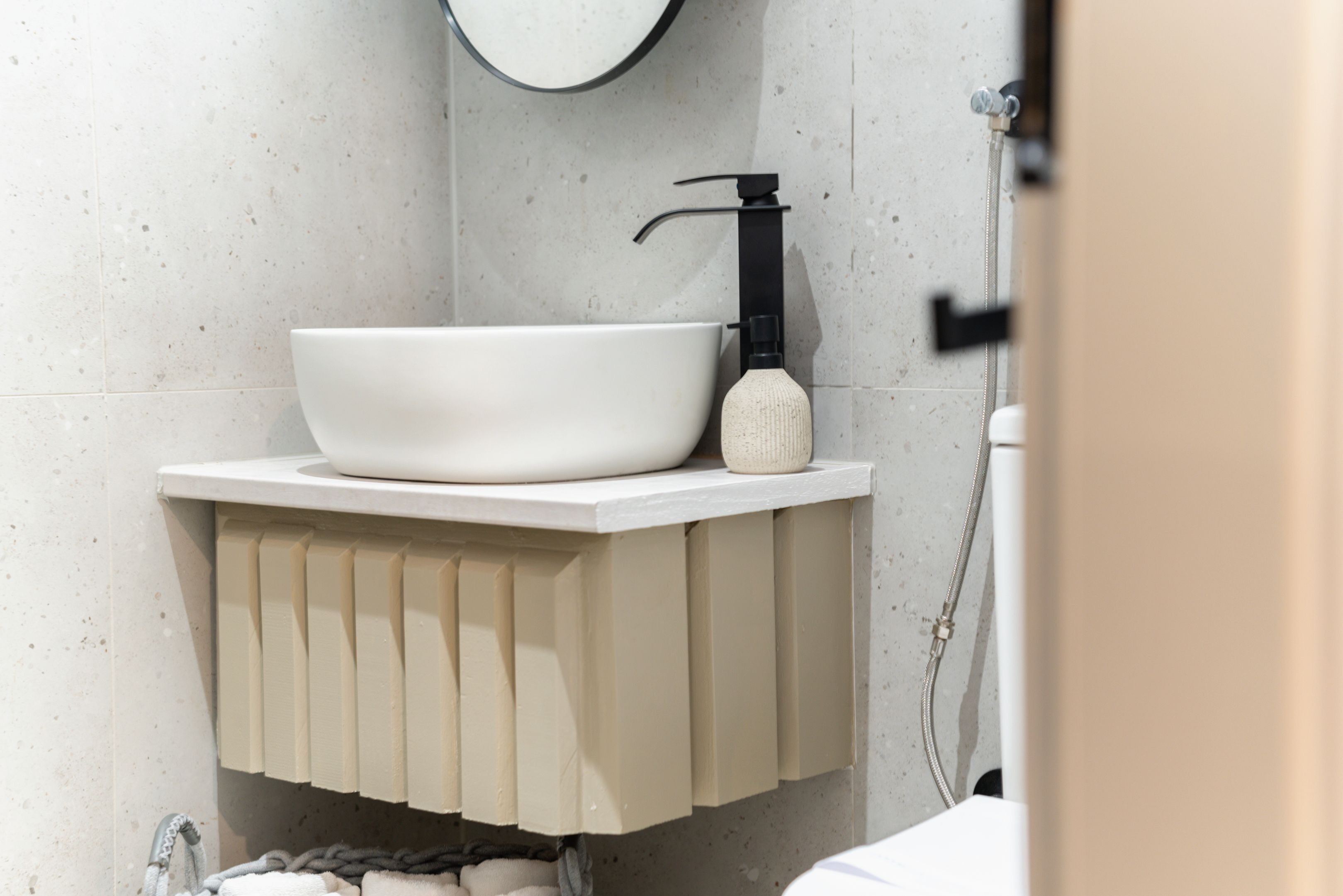 Un baño con lavamanos blanco, grifo negro y toallero.