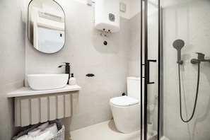 Ein modernes Badezimmer mit Waschbecken, Toilette und Dusche – alles in Weiß.