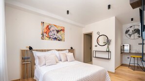 A bedroom with a bed, a painting, a clock, and a small desk with a chair. - Hygge Rooms Split (Split)