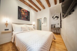 Ein Schlafzimmer mit einem Bett, einem Gemälde, einer Wanduhr und einem kleinen Tisch mit einem Stuhl.