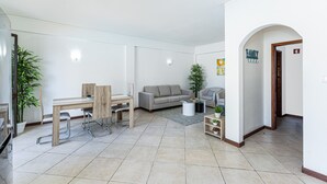 Ein modernes Wohnzimmer mit Essbereich, einem grauen Sofa und einem kleinen Tisch mit Pflanze.