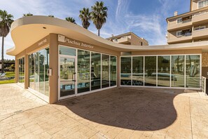 A modern building with a curved facade, large glass windows, and a sign reading 'Piscina Interior.' - Portimão Resort Private Parking & Pool (Portimão)