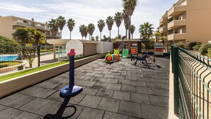 Ein Spielplatz mit Basketballkorb, Fitnessgeräten und im Hintergrund Palmen.