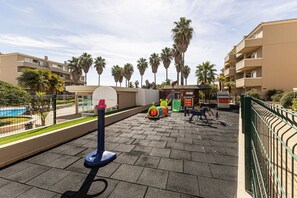 A playground with a basketball hoop, exercise equipment, and palm trees in the background. - Portimão Resort Private Parking & Pool (Portimão)