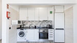 Cuina compacta amb rentadora, forn, microones i nevera.