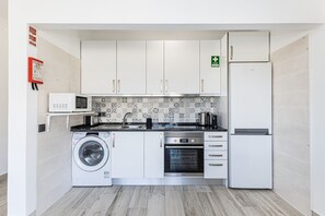 Eine kompakte Küche mit Waschmaschine, Backofen, Mikrowelle und Kühlschrank.