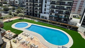 Un complex d'apartaments modern amb piscina i zona d'estar a l'aire lliure.