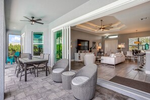A patio area with a table and chairs, a ceiling fan, and a view of the interior. - SWEETWATER BAY - Waterfront Cape Coral Pool house 3/2 fenced yard, kayaks, bikes (Cape Coral)
