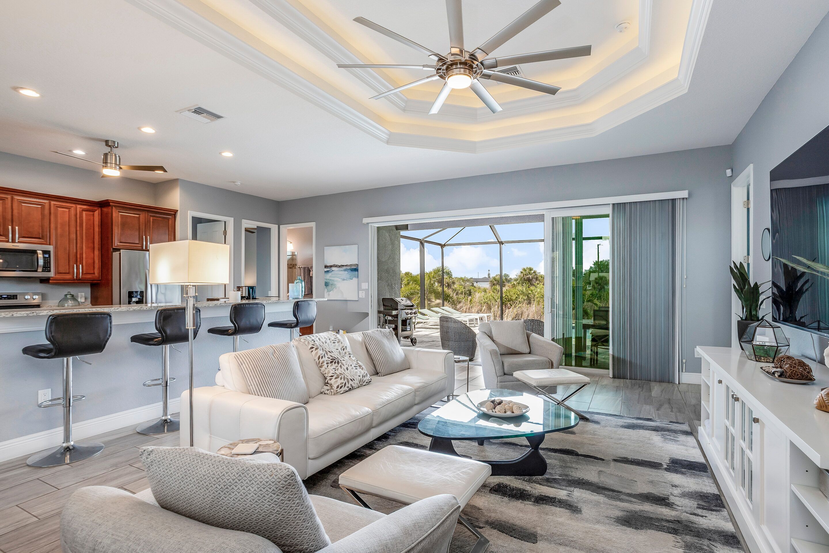 A modern living room with a sofa, chairs, a coffee table, and a ceiling fan.