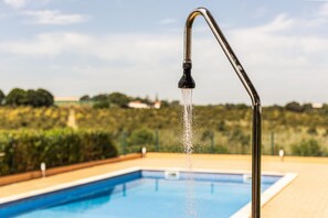 Ein Schwimmbecken mit einem Wasserhahn, aus dem Wasser spritzt, umgeben von Grünpflanzen.