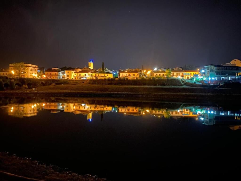 Une vue nocturne d’une zone riveraine, où les bâtiments se reflètent dans l’eau.