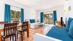 Una habitación amplia con cama, sofá, mesa de comedor con sillas y televisión.