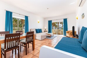A spacious room with a bed, a sofa, a dining table with chairs, and a TV. - Porto de Mos -  Nucleo 2 (Lagos)