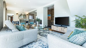 Ett modernt vardagsrum med en soffa, fåtöljer, ett soffbord, en tv och en vägg av sten.