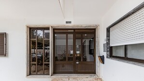 A building entrance with a sliding glass door, a sign indicating 'Lote 30', and a tiled floor. - Cozy Place Lagos Apartment | Beach | Couples & Nom (Lagos)