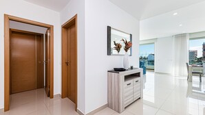 Ein modernes Interieur mit Holztür, weißer Wand, Spiegel und Blick durch ein großes Fenster.