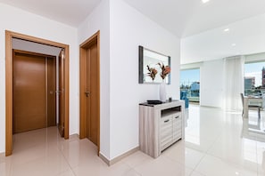 Ein modernes Interieur mit einer Holztür, einer weißen Wand, einem gerahmten Spiegel und einem weißen Schrank.