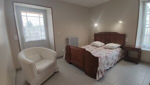 Ein Schlafzimmer mit Bett, Stuhl, Heizkörper und Fenster.
