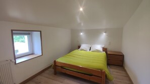 A bedroom with a bed, bedside table, window, and radiator.