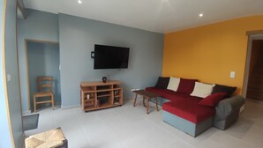 Ein Wohnzimmer mit einer Couch, Fernseher, Holzstuhl und Unterhaltungseinheit.