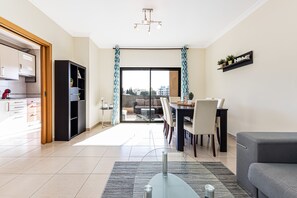 A modern living room with a dining area, a kitchen, and a sliding glass door leading to an outdoor space. - Encosta By The Marina, Beach & City Center (Lagos)