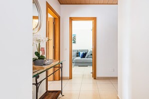 A hallway with a wooden door leading to a living area with a sofa and cushions. - Encosta By The Marina, Beach & City Center (Lagos)