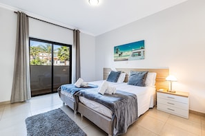 A hotel room with a bed, a nightstand, a lamp, a painting, and a view through a sliding door. - Encosta By The Marina, Beach & City Center (Lagos)