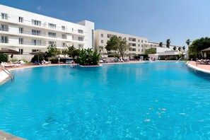 A swimming pool surrounded by white buildings with balconies, palm trees, and lounge chairs. - Marina Garden View in Lagos (Lagos)