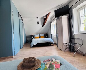 Een slaapkamer met een bed, een stoel, een televisie en een raam.