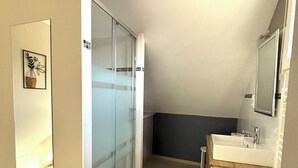 A bathroom with a glass shower enclosure, a sink with a wooden vanity, and a mirror above the sink. - A comfortable, air-conditioned bed-and-breakfast on the Grands Crus Route in Gilly (Gilly les Citeaux)