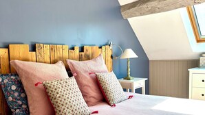 A bedroom with a sloped ceiling, a wooden headboard, a bedside lamp, and a floral-patterned pillow. - A comfortable, air-conditioned bed-and-breakfast on the Grands Crus Route in Gilly (Gilly les Citeaux)