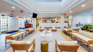 A spacious lobby with wicker furniture, a central round table, and a reception desk. - 2nd Floor Condo w/ Basketball Court, Restaurant, Balcony, Gym, Near Theme Parks (Davenport)